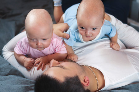 Young father with his newborn twins lying in bed. Selective focusの写真素材