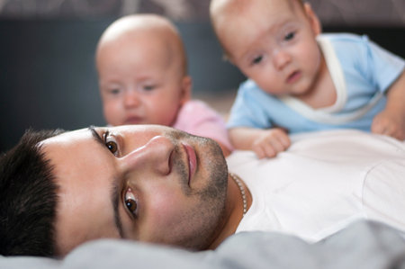 Young father with his newborn twins lying in bed. Selective focusの写真素材