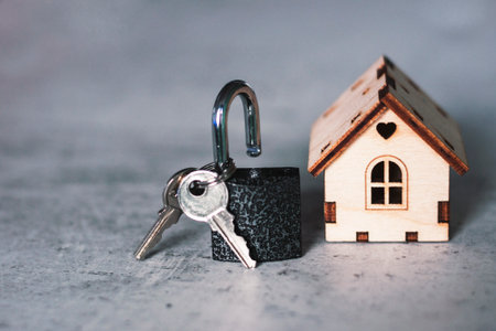 Model of a wooden house with a lock and keys on a gray background. Mortgage concept. Selective focus.の写真素材