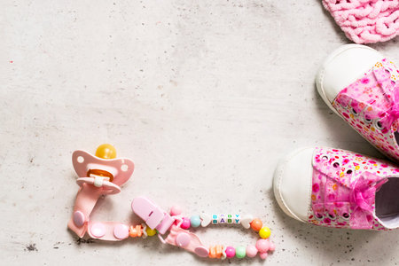 Pink booties, nipple and pink plaid on a gray background. The concept of expecting a baby girl,...