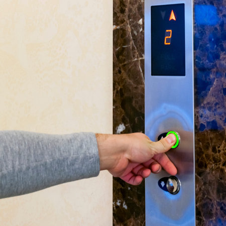 Finger presses the elevator button. Green button. Hand reaches for the button of the elevator call