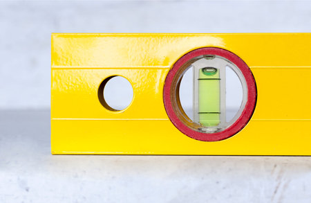 Construction tools a bright yellow level on a light concrete background