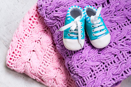 Baby booties pink and blue on a knitted bright microfiber rug. Ivf pregnancy concept