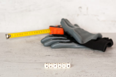 Black construction gloves and a building tape on the background of a concrete wall. In the...