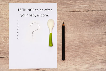 Caption 15 things to do after your baby is born. White A4 sheet on a wooden background with a question markの写真素材