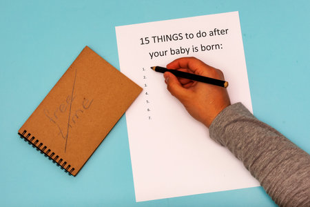 Caption 15 things to do after your baby is born. White A4 sheet on a blue background. Crossed inscription free timeの写真素材
