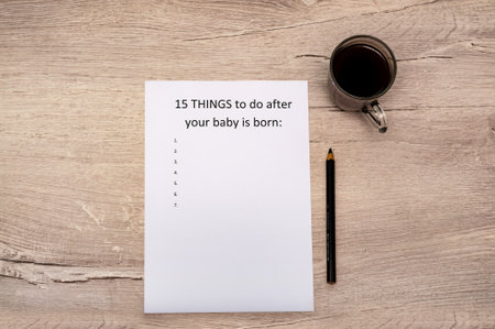 Caption fifteen things to do after your baby is born. White A4 sheet on a wooden background. A cup of coffeeの写真素材