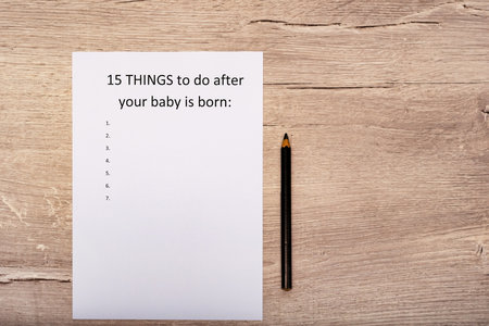 Caption fifteen things to do after your baby is born. White A4 sheet on a wooden backgroundの写真素材