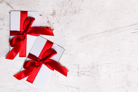 Two white bank cards tied with a red bow. Gift cards