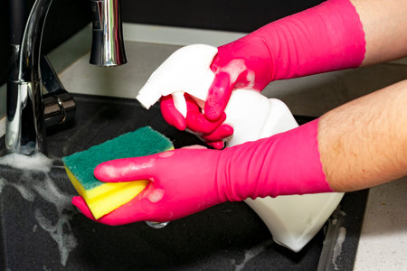 The process of washing the sink, hands closeup. Putting detergent on the dish sponge. Cleaning