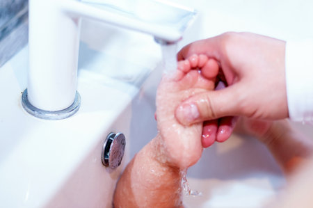 Dad washes the baby in the sink. Closeup of little feet. Paternity.の写真素材
