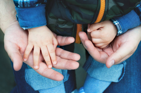Son on his father's lap in the park. paternity. Dad with a child on the street.