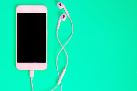 White smartphone on the green background with headphones. View from aboveの写真素材