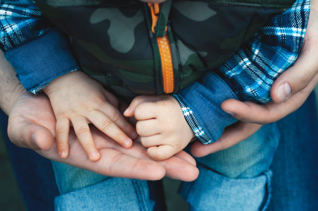 Son on his father's lap in the park. paternity. Dad with a child on the street.の写真素材