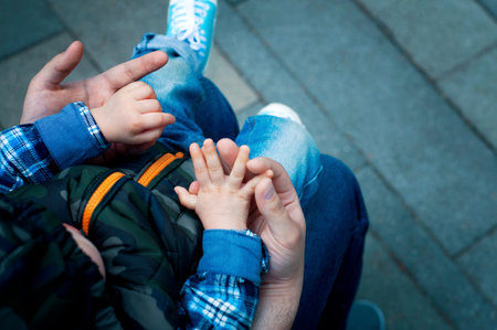 Son on his fathers lap in the park. paternity. Dad with a child on the streetの写真素材