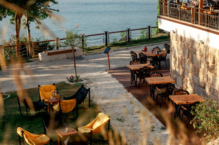Armchairs bags and tables on the grass in a cafe. The sea in the background. The interior of the...