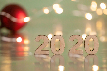 The inscription 2020, New Year and Christmas, from behind blurred dots of light on a blue background and red balls on the Christmas tree. Christmas and holidayの写真素材
