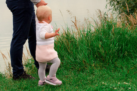 Dad teaches daughter to walk in nature. Father and daughter. First steps