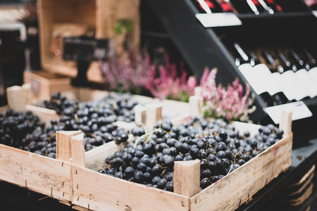 Dark grapes in a wooden box on a store counter. Wine in the background. Creative trade, decoration solutionsの写真素材