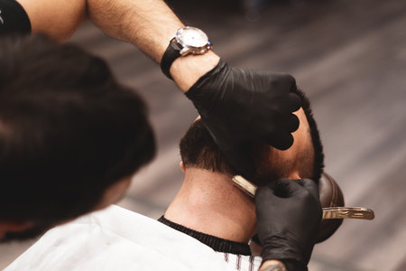 Shaving a beard in a barbershop with a dangerous razor. Barber Shop Beard Care. Drying, cutting, cutting a beard. Selective focusの写真素材