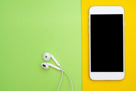 Music, gadgets, music lover. White smartphone on the purple and blue background with headphones. View from above. Flat lay, top viewの写真素材