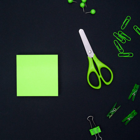 Educational composition, stationery. Green stationery and green notebook on a black background. Flat...