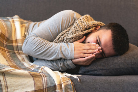 Disease. Cheer at home. A young man is sick, is treated at home. Blows her nose into a napkin, runny nose. Infection, epidemic, bacillus carrier.の写真素材