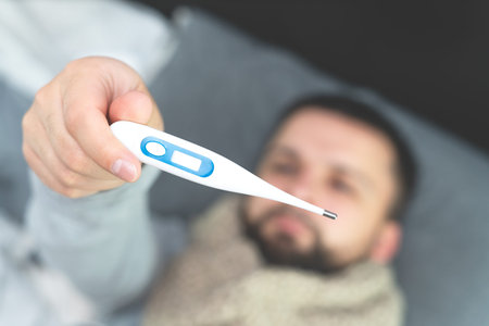 Disease. Cheer at home. A young man is sick, is treated at home. Body temperature measurement. In...