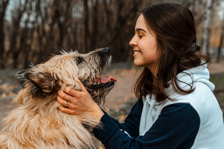 Animal training. A volunteer girl walks with a dog from an animal shelter. Girl with a dog in the autumn park. Walk with the dog. Caring for the animals.の写真素材