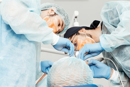 Two male dentists perform an operation on a patient. Surgery in dentistry. Professional uniform の写真素材