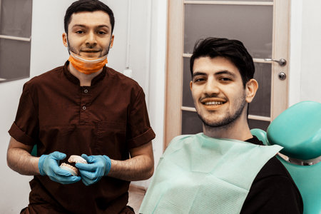 A young dentist discusses a diagnosis and treatment plan with a patient. Discussion and demonstration of treatment results. Health care, aesthetic medicine.の写真素材
