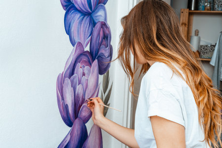 Artist. Designer. Young girl artist paints on a wall indoors. Interior Design. The creative process.の写真素材