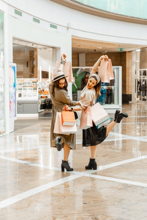Shopping and entertainment, mall inside. Two beautiful girls with paper bags at the mall. The joy of consumption, Gift shopping, holiday.の写真素材
