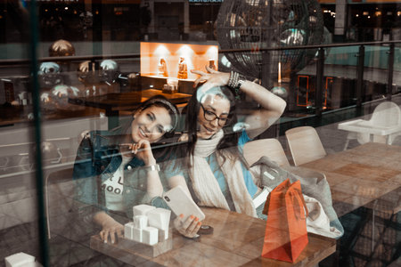 Cafes and bars. Two girls are sitting at a cafe table. Discussion of shopping. Girlfriends in a...