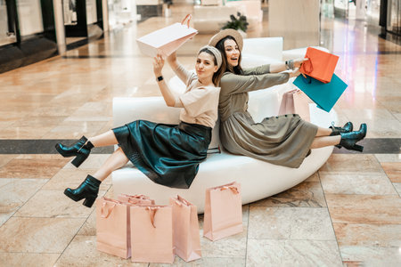 Girls are resting on the couch in the mall. Shopping, entertainment and leisure. Break in purchases.の写真素材