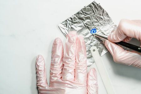 Manicurist at work in the office. Drawing gel polish on tips, creating a picture. Equipment and inventory of a manicure cabinetの写真素材