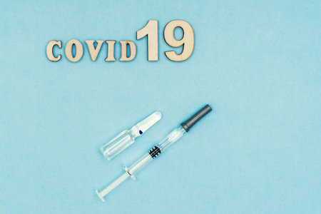 Coronavirus, covid-19. The inscription covid-19 on a blue background. Self-isolation and quarantine, personal protective equipment, ampoule and syringeの写真素材