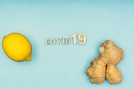 Coronavirus, Covid-19. The inscription covid-19, lemon and ginger on a blue background. Self-isolation and quarantine, personal protective equipment and healthy nutrition. Natural vitamins during illness.の写真素材