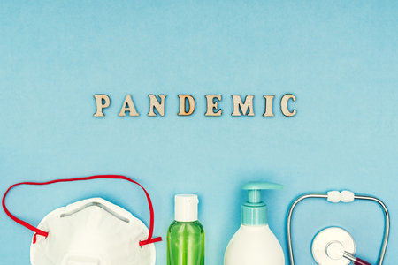 Coronavirus, Covid-19. The inscription Pandemic, a protective mask, antiseptic and dispenser for soap soap on a blue background. Self-isolation and quarantine, personal protective equipmentの写真素材