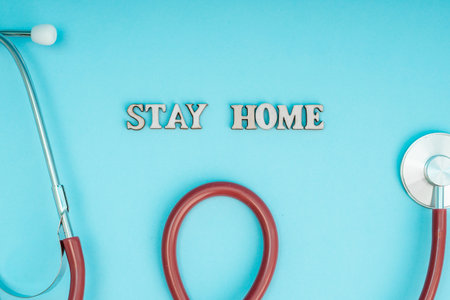 Coronavirus, covid-19. The inscription stay home on a blue background. Self-isolation and quarantine, personal protective equipment, phonendoscope and stethoscope.の写真素材