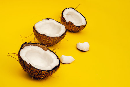 Parts of coconut on a colored background. Close up. Fresh ripe coconut broken into pieces