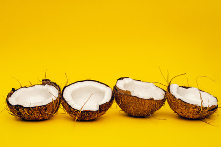 Parts of coconut on a colored background. Close up. Fresh ripe coconut broken into piecesの写真素材