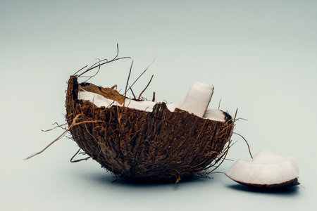 Parts of coconut on a colored background. Close up. Fresh ripe coconut broken into piecesの写真素材
