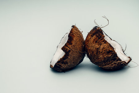 Parts of coconut on a colored background. Close up. Fresh ripe coconut broken into piecesの写真素材