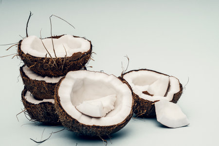 Parts of coconut on a colored background. Close up. Fresh ripe coconut broken into piecesの写真素材