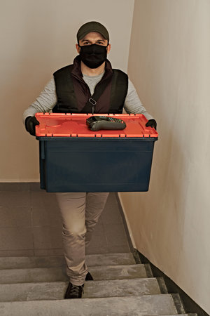 A courier in a protective mask delivers food. Delivery under quarantine. Pandemic.