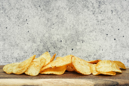 Corrugated potato chips on a wooden board. Snack, ready meal menu, junk food. Close upの写真素材