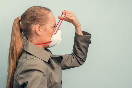 A girl is putting on a protective mask. Respiratory protection from coronavirus. Personal protective equipment for a pandemic of a viral infection. Covid-19.の写真素材