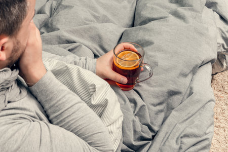 Disease. Cheer at home. A young man is sick, is treated at home. Blows her nose into a napkin, runny nose. Infection, epidemic, bacillus carrier.の写真素材