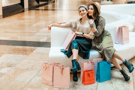 Girls are resting on the couch in the mall. Shopping, entertainment and leisure. Break in purchases.の写真素材